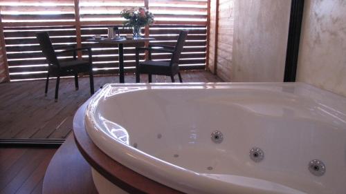 纳博讷Ile du Gua Suites的带浴缸的客房内配有桌椅