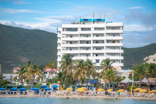 辛普森湾Atrium Beach Resort and Spa St Maarten a Ramada by Wyndham的海滩上的酒店,配有椅子和遮阳伞