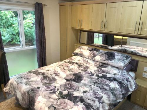 斯凯格内斯Gold Standard Caravan on South View Park的一间卧室配有一张带花卉棉被的床