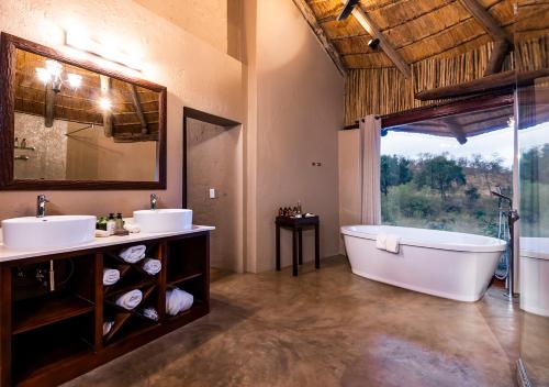 Makalali Game Reserveaha Makalali Private Game Lodge的一间带两个盥洗盆、浴缸和窗户的浴室