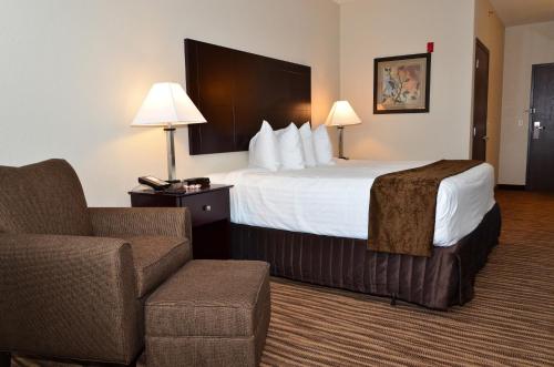ClarionCobblestone Inn & Suites - Clarion的配有一张床和一把椅子的酒店客房