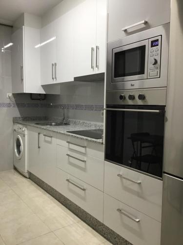 米拉多罗Apartamento Lua的厨房配有白色橱柜和微波炉