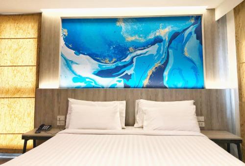 曼谷叻差达迷你R酒店的一间卧室,上方有一张画作