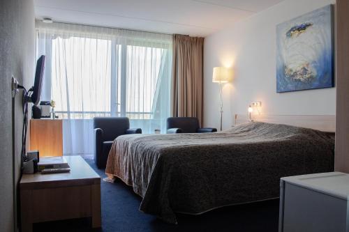 比伦布伦海滨酒店的酒店客房设有一张床、两把椅子和一扇窗户。