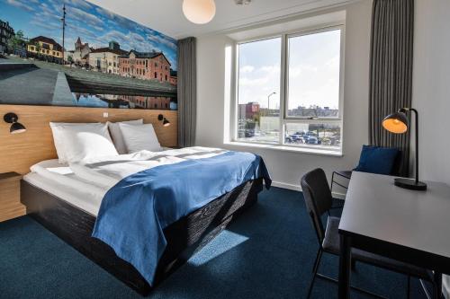 奥尔堡KOMPAS Hotel Aalborg的配有一张床、一张书桌和一扇窗户的酒店客房