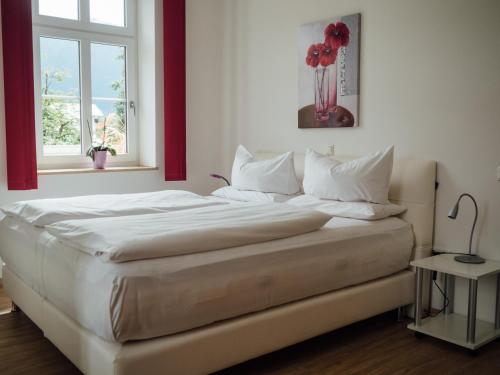 奥巴拉马高加尼阿梅高尔霍夫酒店的一张带白色床单和红花花瓶的床