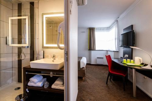 兰斯钟楼雷姆中央大教堂酒店的一间带水槽和镜子的浴室以及一张书桌