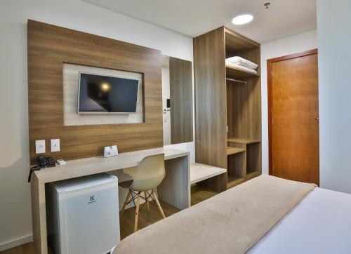 卡里亚西卡Nobile Inn Meridional Cariacica的一间卧室配有一张床、一张书桌和一台电视。