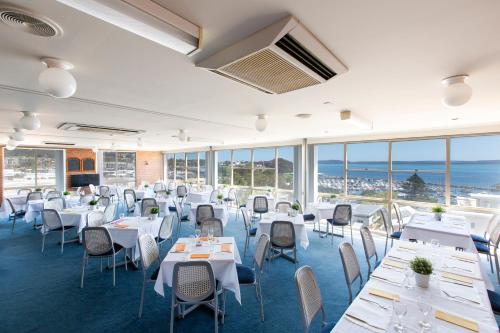 尼尔森湾滨海度假村的餐厅设有白色的桌椅和窗户。