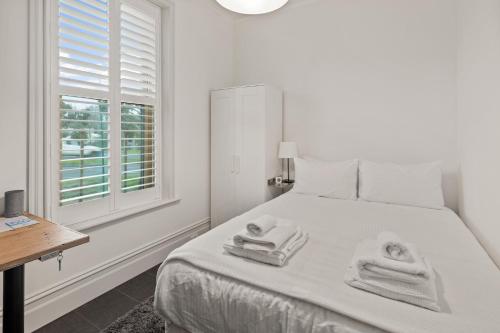 墨尔本Work Sleep Live Melbourne的白色卧室,配有带窗户的床上毛巾