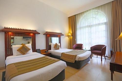 新德里阿肖克乡村度假酒店的酒店客房设有两张床和窗户。