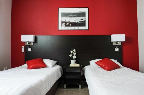 波尔多巴黎圣母院酒店的红色墙壁的酒店客房内的两张床