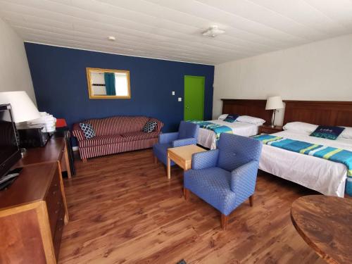 WaubausheneAll Tucked Inn的酒店客房带两张床和一张桌子以及椅子。