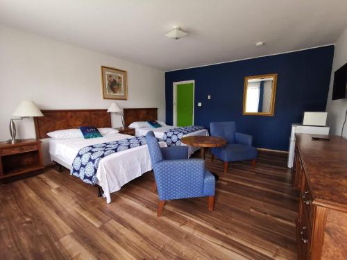 WaubausheneAll Tucked Inn的酒店客房带两张床和一张桌子以及椅子。