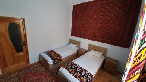希瓦"YOQUT HOUSE" guest house in the centre of ancient city的配有门和地毯的客房内的两张床
