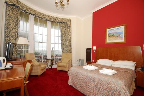 布莱顿霍夫海滩酒店的酒店客房设有一张床、一张书桌和窗户。