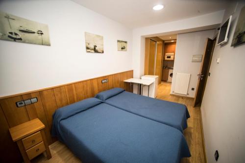 索里亚Hostal Caballeros的一间设有蓝色床和一张桌子的小卧室