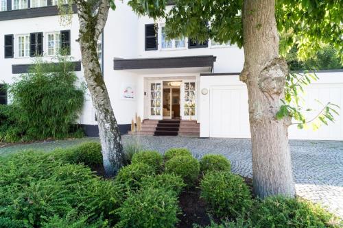 杜塞尔多夫Hotel Villa im Park的前面有两棵树的白色房子