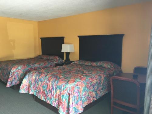 中心城市卡罗诺达汽车旅馆的两张床位于带黄色墙壁的酒店客房