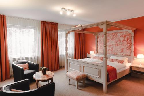 埃森升高文霍夫酒店的一间卧室配有一张天蓬床和一把椅子