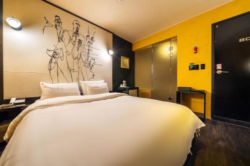 九里市Guri Lexy Hotel的一张白色的大床,位于拥有黄色墙壁的房间