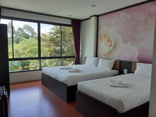 Ban Phlu Phliบลูออคิดรีสอร์ท ตรัง的酒店客房设有两张床和大窗户。