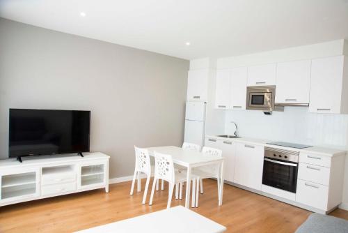 格罗韦L1 Apartamento O Grove Centro, Aire acondicionado, parking的厨房配有白色橱柜和桌椅