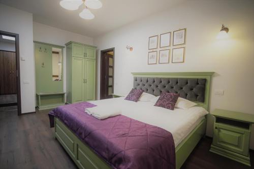 皮亚特拉-尼亚姆茨La Curtea Domneasca的一间卧室配有一张大床和紫色毯子