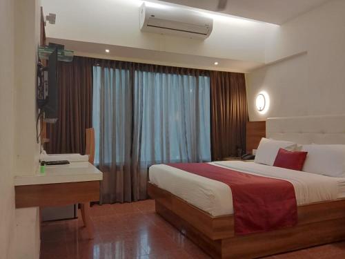 孟买米兰国际大酒店的一间卧室配有一张床、一张书桌和一个窗户。