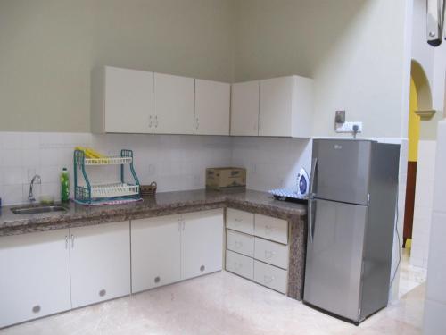 马六甲韦恩班达亚卡巴酒店的厨房配有白色橱柜和不锈钢冰箱