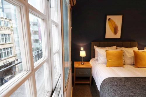 利兹Heart of Leeds City Centre Living - Sleeps 6的一间卧室配有一张带黄色枕头的床和一扇窗户
