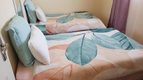埃祖尔韦尼Mdzimba Mountain Lodge的两张带枕头的床和一张带叶子的毯子