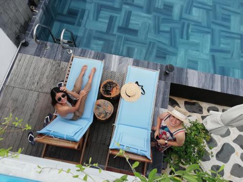岘港Santori Hotel Da Nang Bay的两人坐在游泳池旁的椅子上