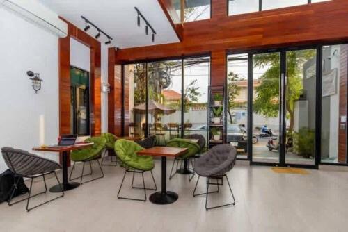 金边Ptas Tauch Residence的餐厅设有绿色的椅子和桌子以及窗户。