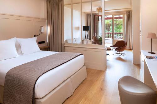 派拉索梅Villa du Pyla的酒店客房设有一张大床和一张书桌。