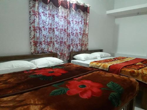 蒙纳Munnar Brindavan Cottage的客房设有两张床和鲜花窗户。