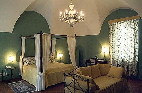 Cocconato隆卡德马特勒蒂酒店的一间卧室配有一张床、一张沙发和一个吊灯。