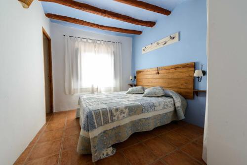 La CodoñeraCasa rural Lo Regolfo的一间卧室配有一张蓝色墙壁的床和一扇窗户