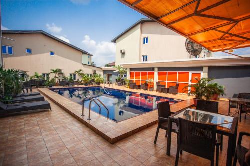 哈科特港Visa Karena Hotels的大楼旁的游泳池配有桌椅