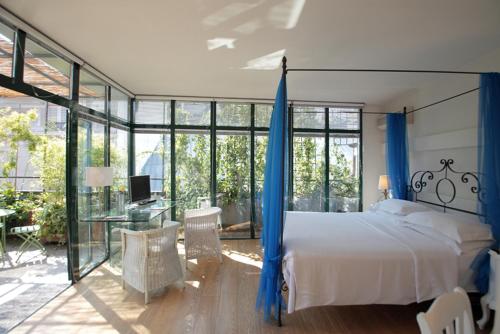 米兰安提卡洛坎达酒店的一间卧室配有一张带蓝色窗帘的床和一张书桌