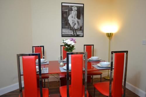 剑桥Epicsa - 3 Bedroom Family & Corporate Stay, Garden and FREE parking的一间带桌子和红色椅子的用餐室
