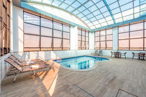 戈亚尼亚微风机场广场酒店的大型客房设有带玻璃天花板的游泳池。
