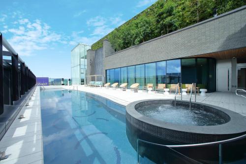 福冈Miyako Hotel Hakata的一座大楼中央的带热水浴池的游泳池