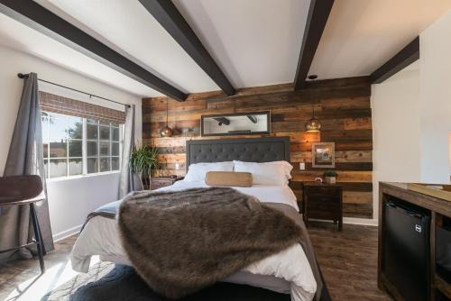 皮斯莫比奇贝壳海滩旅馆的一间卧室设有木墙和一张带毯子的床