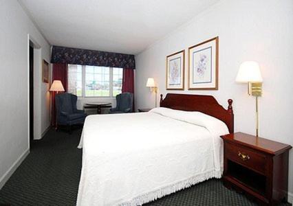 费耶特维尔大使汽车旅馆的酒店客房,配有白色的床和椅子