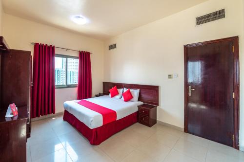 沙迦Al Reem Hotel Apartments的一间卧室配有一张带红色窗帘的大床