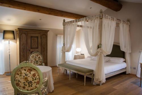 雷吉奥洛纳比拉别墅酒店的一间卧室配有一张天蓬床和一把椅子
