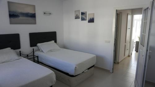 蒂亚斯Apartamento Puerto del Carmen Las Vistas 247的白色墙壁客房的两张床
