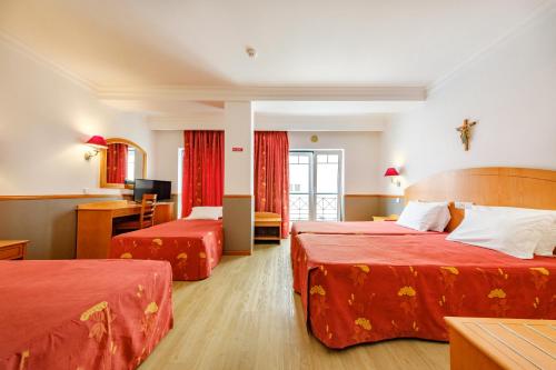 法蒂玛Hotel Santo Amaro - SA Hotels的酒店客房,配有两张带红色床单的床
