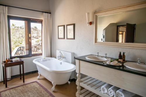 克拉塞利尔自然保护区Last Word Kitara的浴室配有2个盥洗盆、浴缸和大镜子